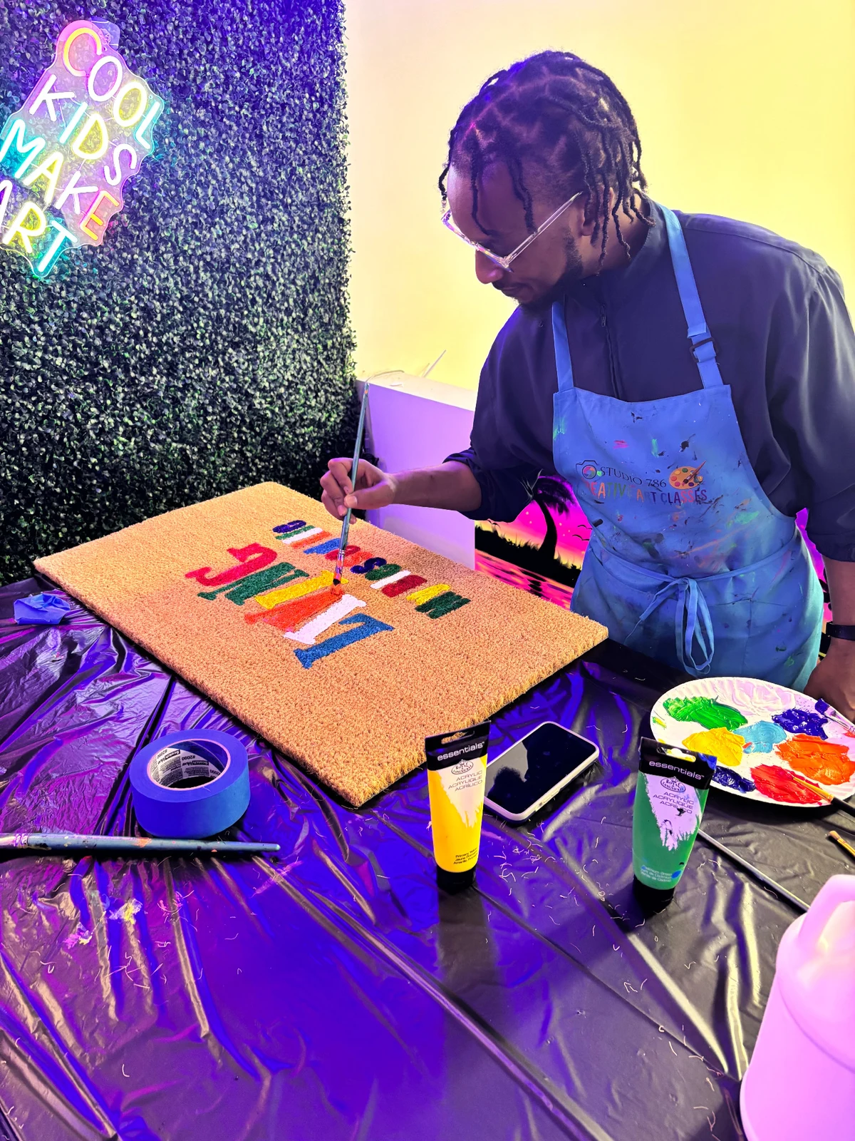 A Studio 786 guest painting a colorful personalized doormat