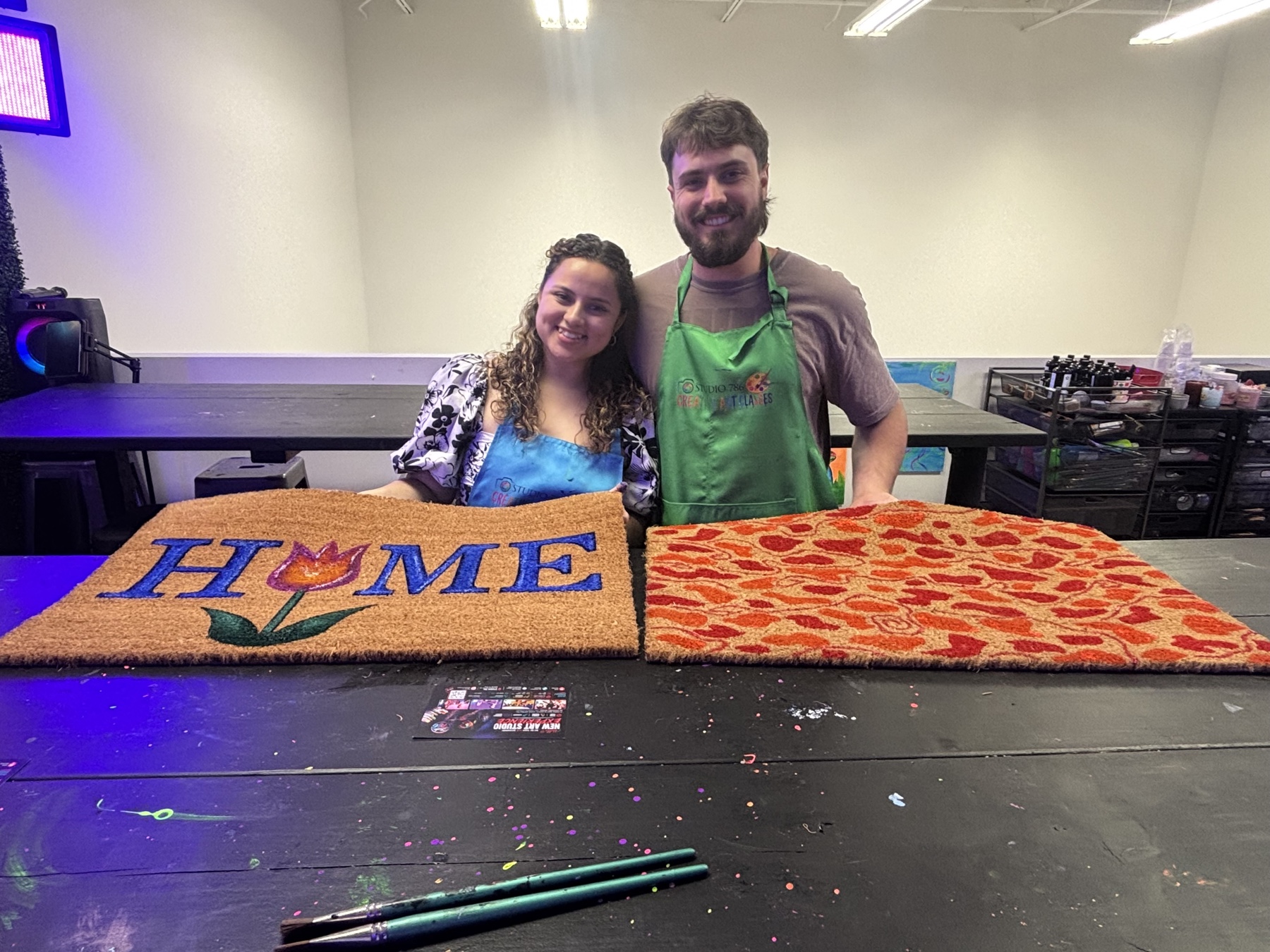 Couple displaying two custom painted doormats at Studio 786 in Houston