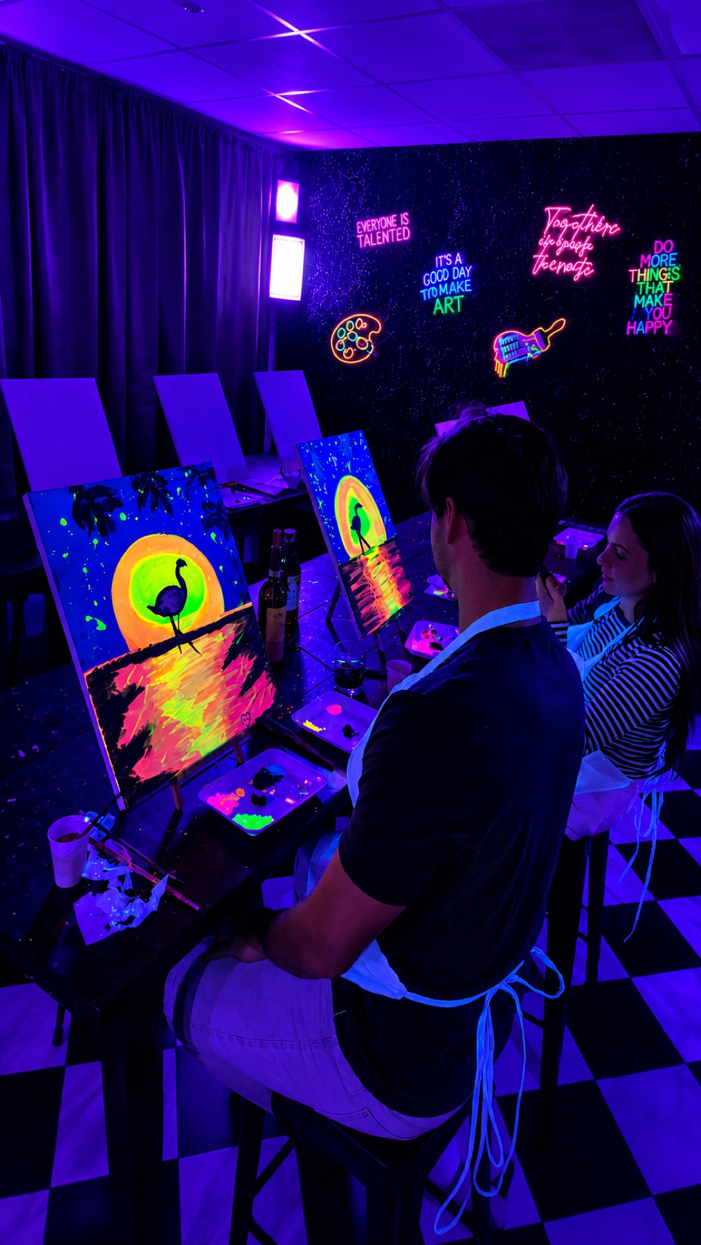 Couple painting glowing flamingo canvases under black lights at Studio 786 Houston