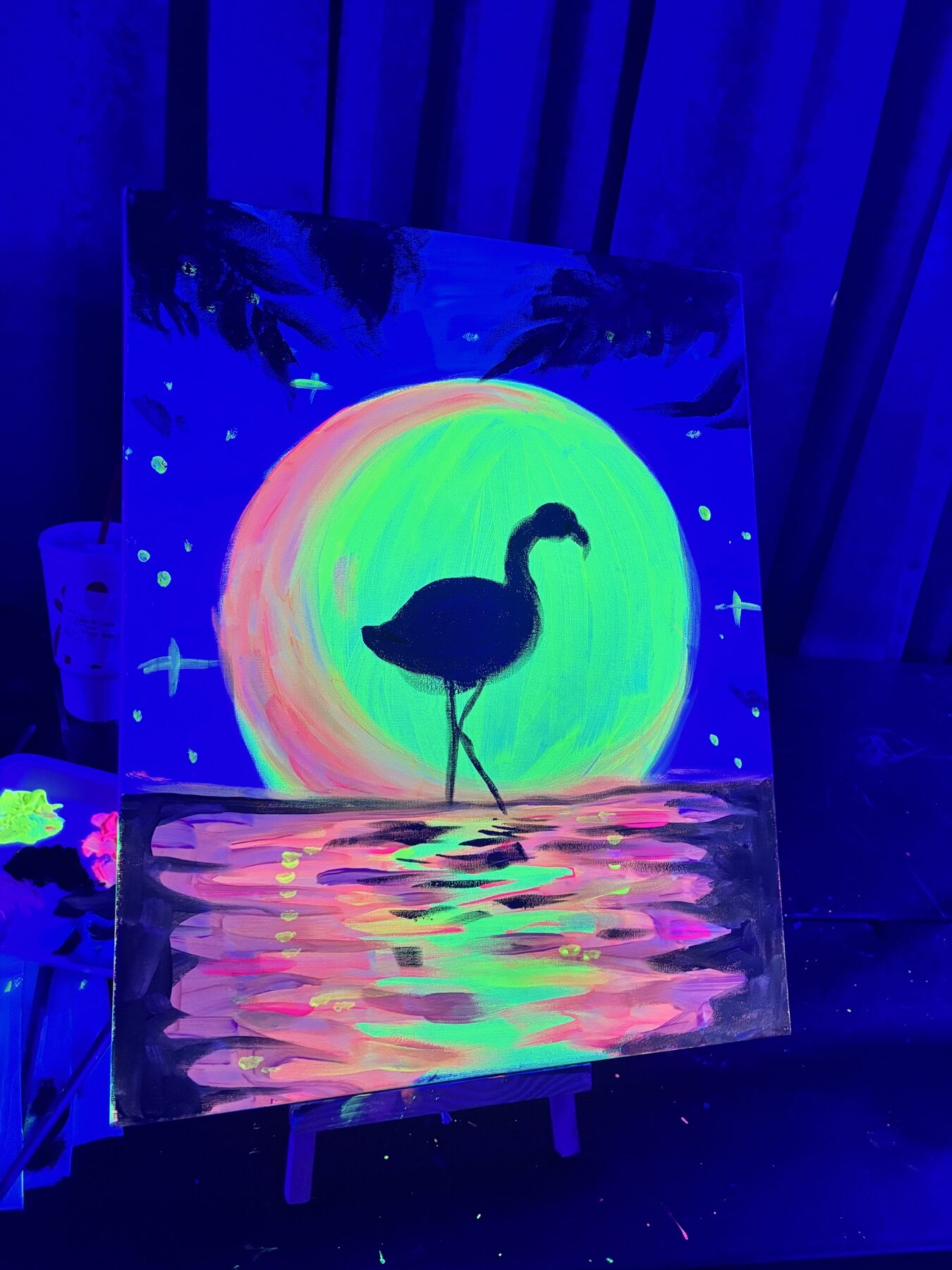 Finished neon flamingo canvas glowing under black lights in a Houston painting class