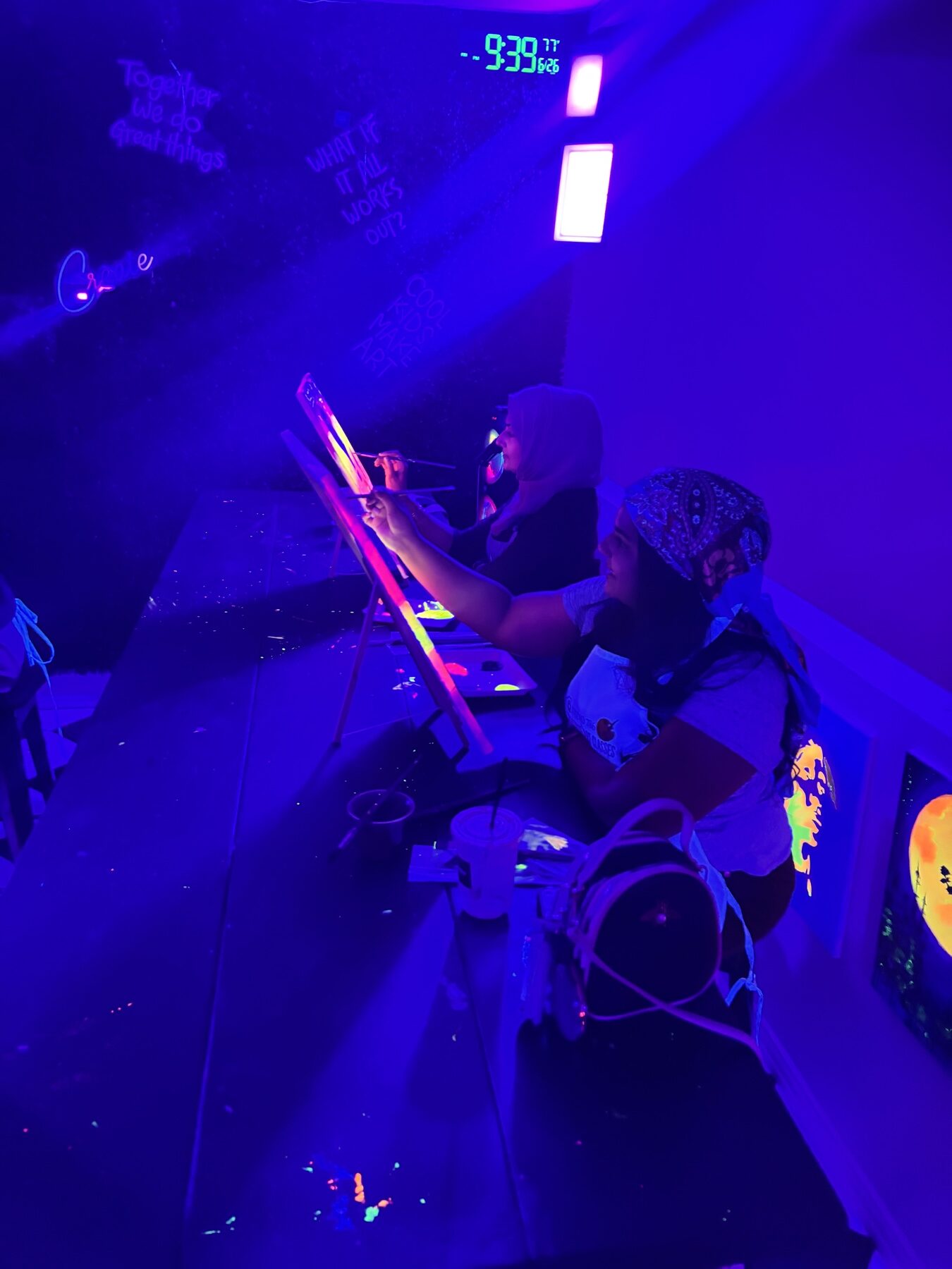 Friends painting glowing canvases together under black lights at Studio 786 Houston
