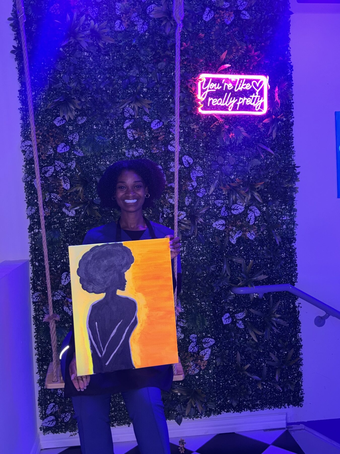 Guest holding a finished neon portrait canvas after a UV glow painting class at Studio 786 Houston