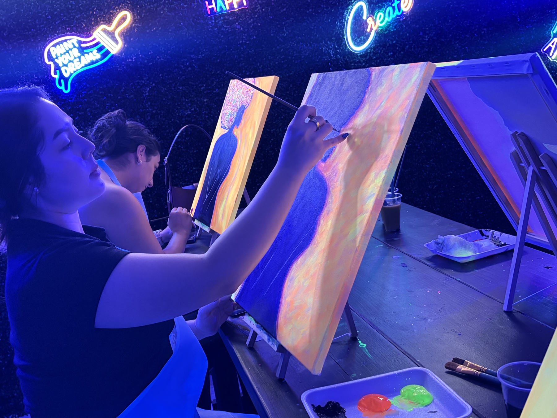 Guest painting a colorful portrait canvas during a UV glow art class in Houston