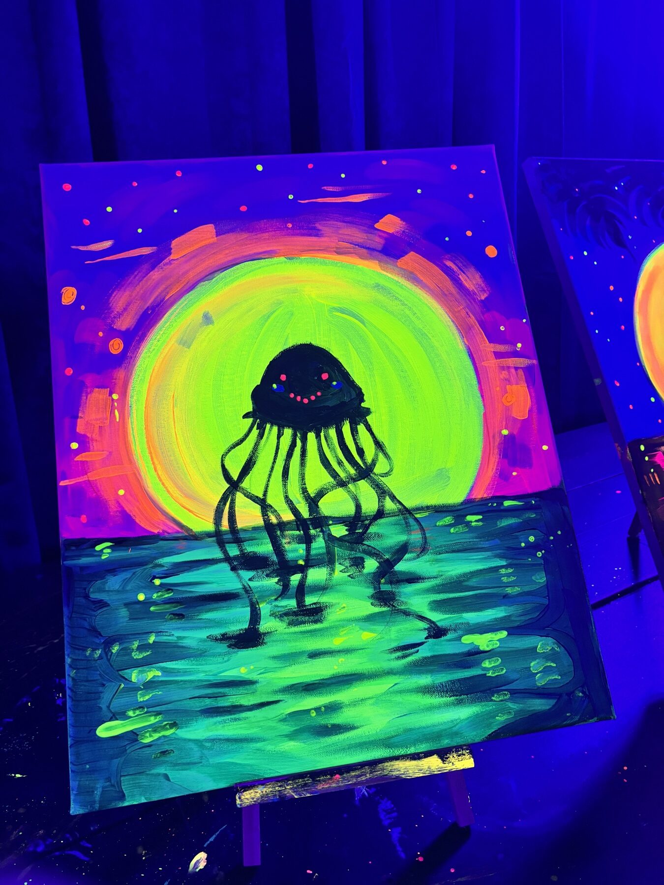 Close-up of a neon jellyfish canvas painted under black lights at Studio 786 Houston
