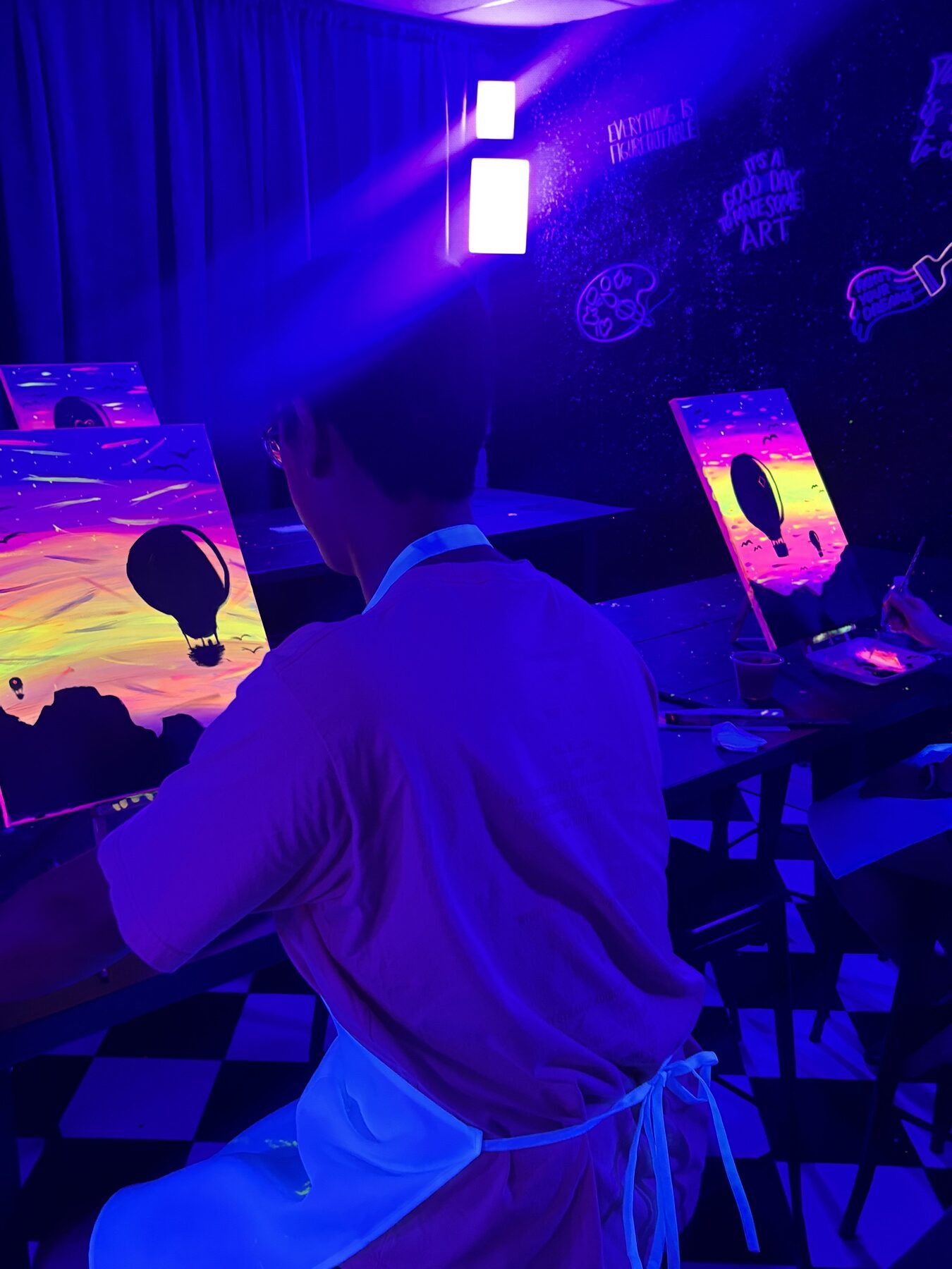 Guests painting neon hot-air-balloon canvases during a Houston UV glow art class